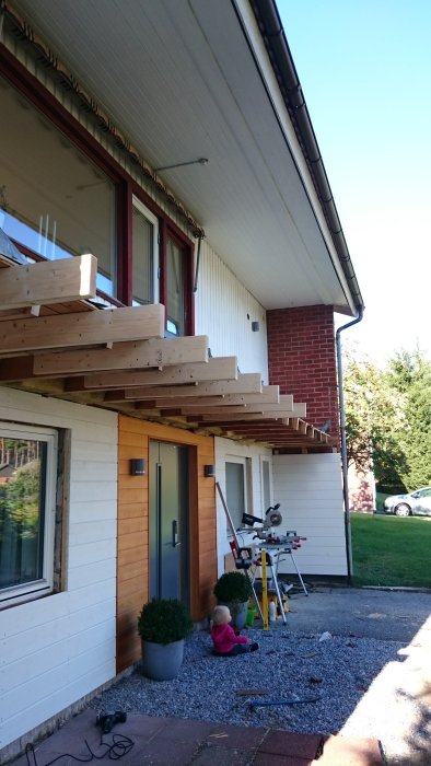 Pågående bygge av balkong längs husets framsida med verktyg och byggmaterial synliga.