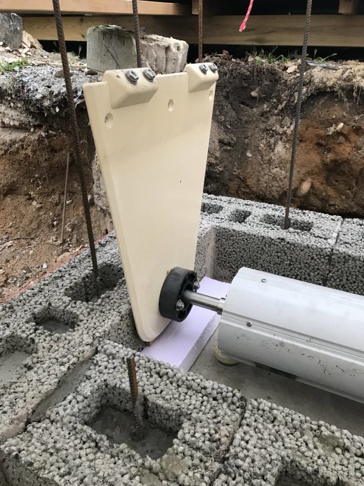 Murningsarbete på en nygjuten betongplatta med en rulle och fästen vid en byggarbetsplats.