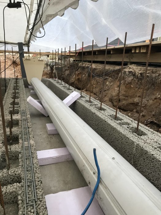Nybetongerad platta med pågående murningsarbete, armeringsjärn och konstruktionsdetaljer synliga.