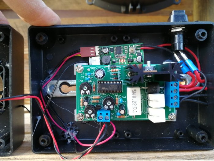 Kretskort monterat i svart låda med kopplade kablar och elektroniska komponenter.