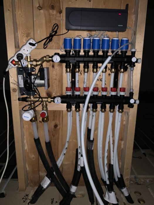 Golvvärmesystem med Uponor fördelare, rör och manifolds och tillfällig skarvsladd ansluten till kontrollenheten.