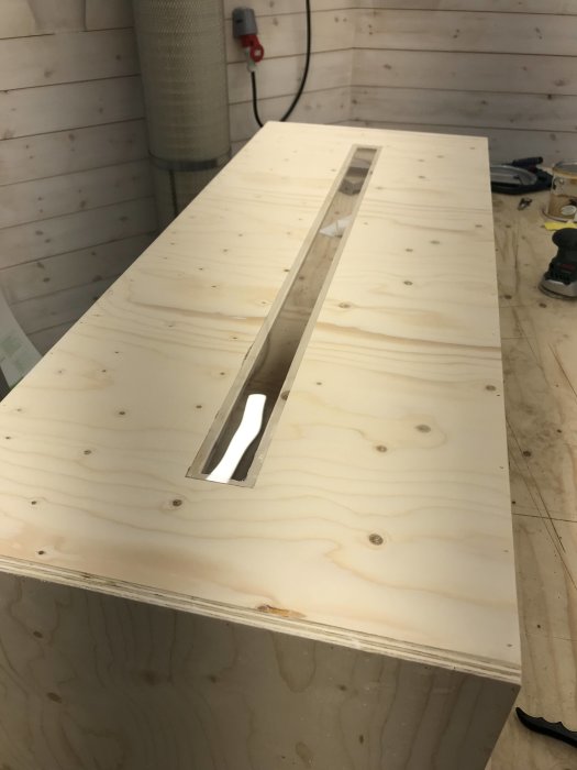 En nyligen byggd spånlåda av plywood med ett genomskinligt siktglas för att kontrollera nivån på spånen inne i lådan.