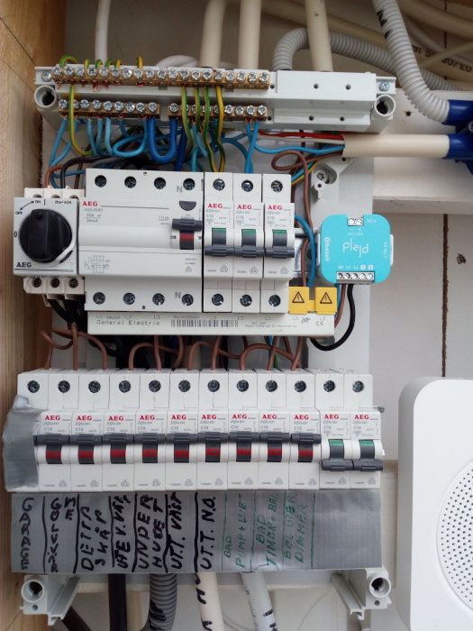 En elektrisk central med PLEJD-enhet installerad för att styra utebelysning, omgiven av AEG säkringar och kablar.