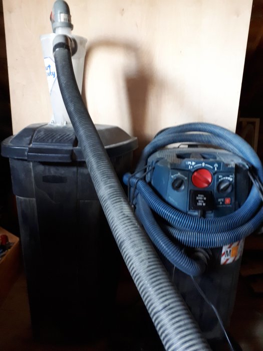 En industriell dammsugare GAS 55 med slangar kopplade till en behållare.