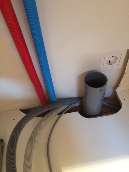Aluminiumskåpbotten med rör och kablar genom en öppning, inklusive en för liten E.V.A och ett avloppsrör.