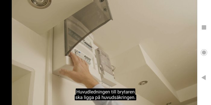 Person som pekar på en öppen elektrisk säkerhetsbrytare på en vägg.