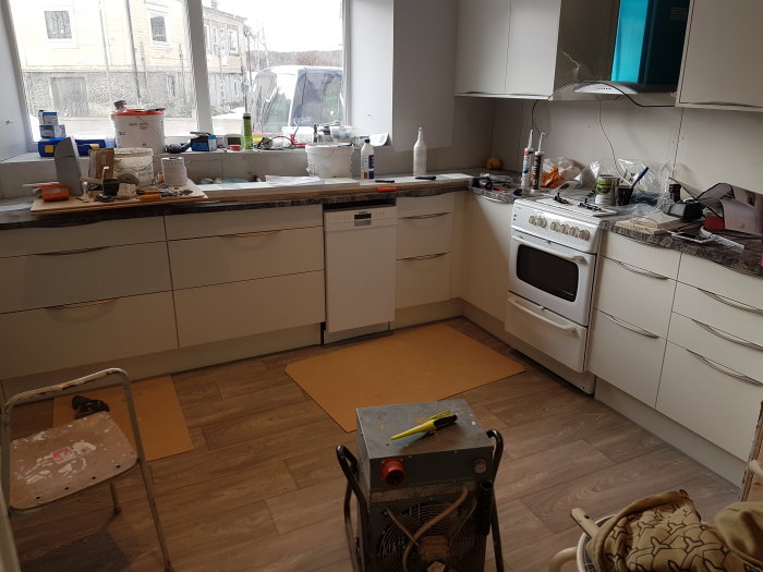 Kök under renovering med nyjusterade luckor och nymonterade handtag, verktyg på golvet.