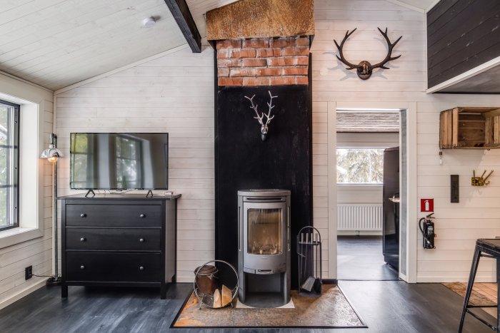 Stilfullt inrett vardagsrum med kamin, tegelvägg och hjorthuvud på väggen.