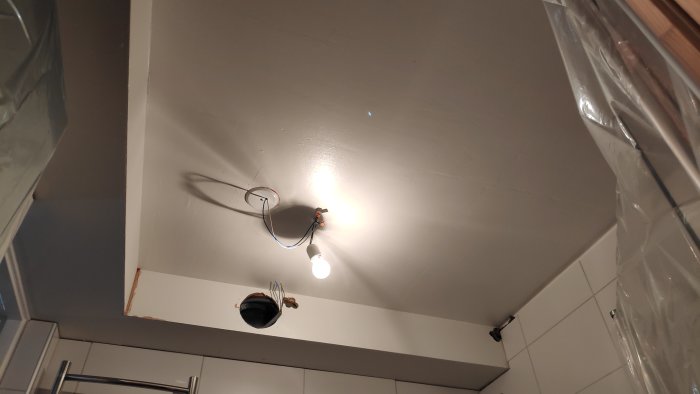 Tak i badrum under renovering med nakna glödlampor och öppna elkablar som väntar på installation av downlights eller annan belysning.
