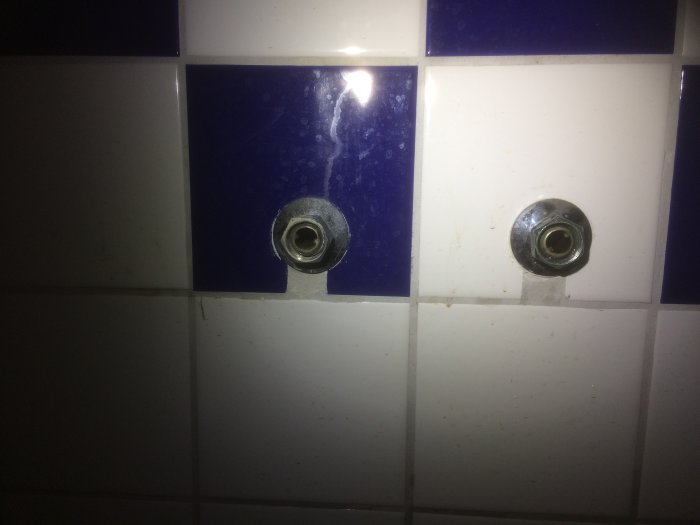 Väggmonterade kopparrör med cc 155 mm för blandarinstallation i badrum med blå och vita kakelplattor.