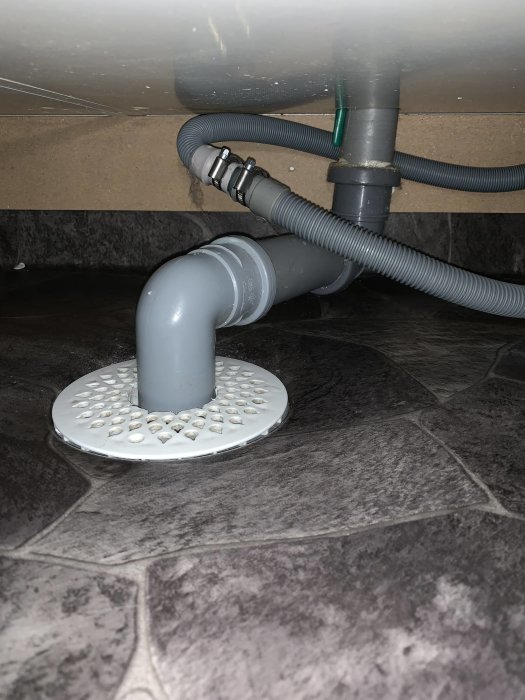 Vattenlås och avloppsslang under tvättstugans handfat, problem med överflödande brunn.