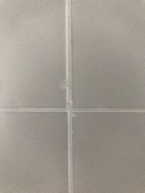 Närbild på kakel i badrum med fokus på fogar mellan plattorna.