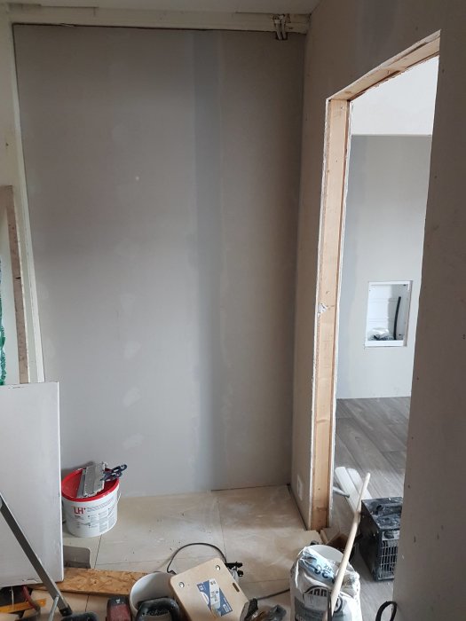 Renoveringsrum med nylagt spångolv och nyuppförd vägg, verktyg och byggmaterial synliga.
