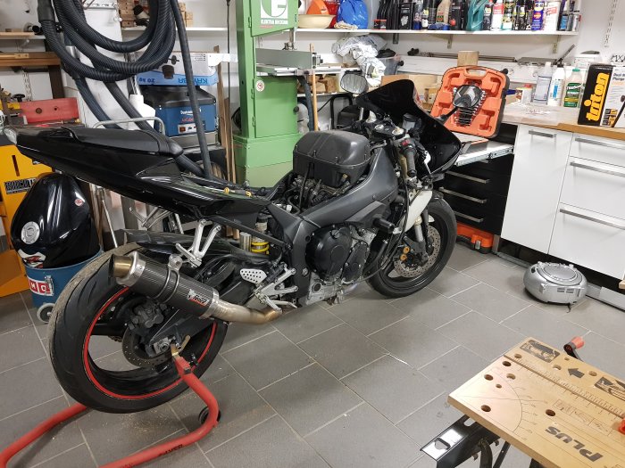 Motorcykel under reparation i en välorganiserad verkstad med diverse verktyg och utrustning.