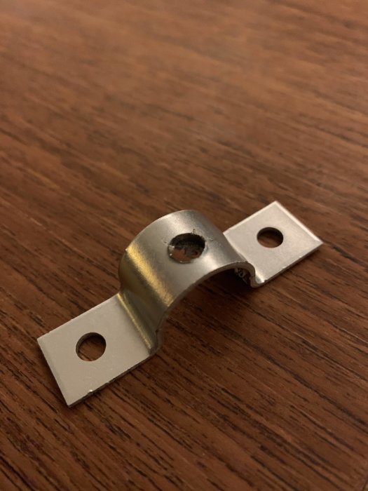 Metallbeslag med centrumhål och två fästpunkter, använd för fästning av armeringsnät.
