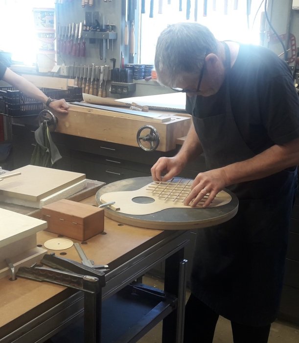 Person i snickeriverkstad arbetar på en gitarrkropp med sugrörsmetoden.