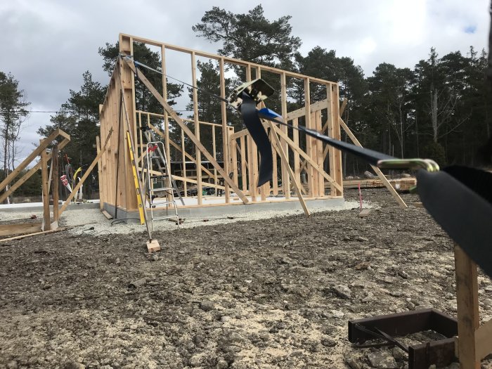 Uppförande av trästomme för hus på betongplatta med verktyg och byggmaterial synliga runtomkring.