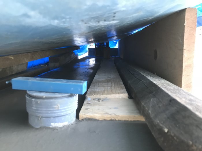 Närbild på en nyslipad betongplatta med justerbara stödben och reglar för anläggningsarbeten.