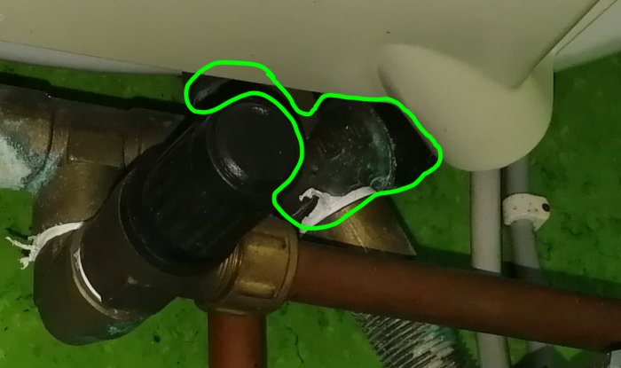 Rörkoppling med inbyggd backventil markerad med grön ring och otydlig siffra på svart yta.
