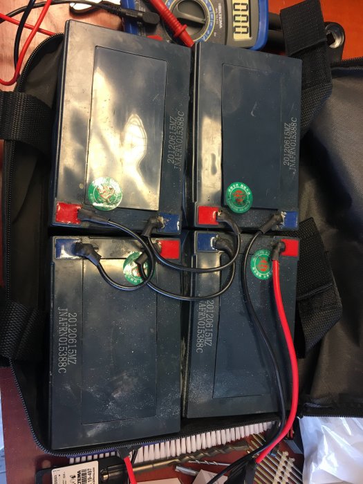 Slitet batteripack med två svarta batterier och anslutna kablar ligger på ett bord, tecken på användning syns.