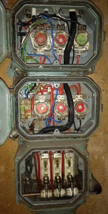 Gammal elektrisk säkringscentral med flera diazed-säkringar och röda kopplingsledningar.