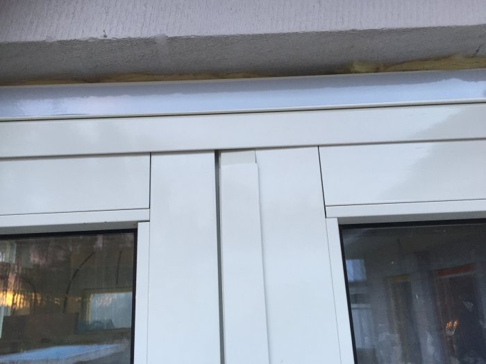 Detalj av ett monterat vitt skjutparti i aluminium med böjd kant från Elitfönster under en betongförlängning.