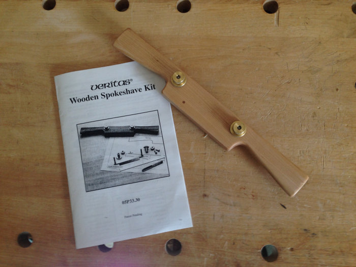 Hemmagjord spånhyvel på en verktygstavla med Veritas instruktionsbok för Wooden Spokeshave Kit.