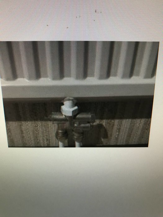 Radiator med ett inkommande rör och stängd ventil, stor mutter där ett element tagits bort.