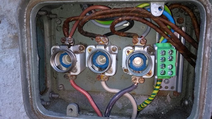 Elektrisk anslutningslåda med säkringar, papper/bly-kabel och en nyinstallerad grön jordplint på DIN-skena.