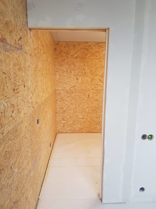 Väggkonstruktion med OSB-skivor och en ofärdig skjutdörröppning i ett byggprojekt.