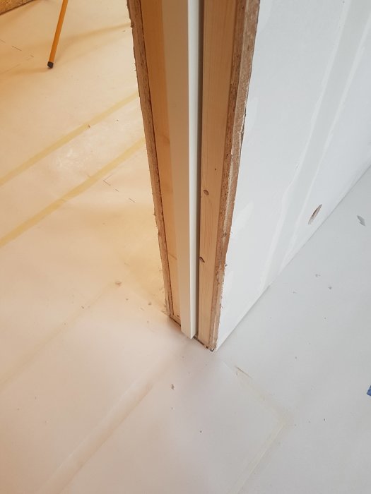 Detaljbild av en oavslutad vägg vid skjutdörr med synliga reglar och gipsplattor.
