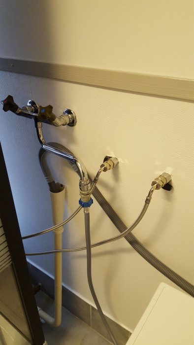 Tvättmaskinskoppling med snabbkoppling på kran, slangar till varm- och kallvatten.