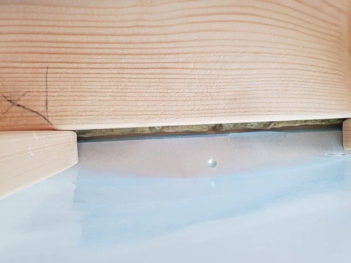 Plastdiffusionsspärr vikt vid kanten av en träglespanel utan att vara korrekt installerad.