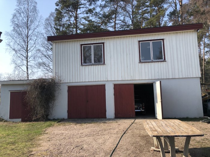 Villa med ett tvåvåningsgarage uppbyggt av lecablock, övre våningen med fönster, i behov av renovering.