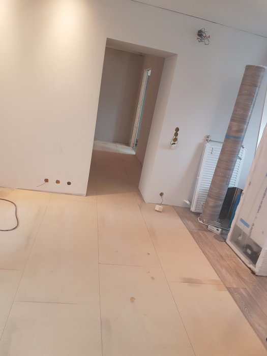 Rum under renovering med osammanhängande golvplattor och vägglister lutade mot väggen.