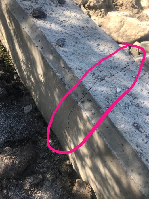 Nyligen uppförd mur med tre stora sprickor markerade med rosa cirkel.