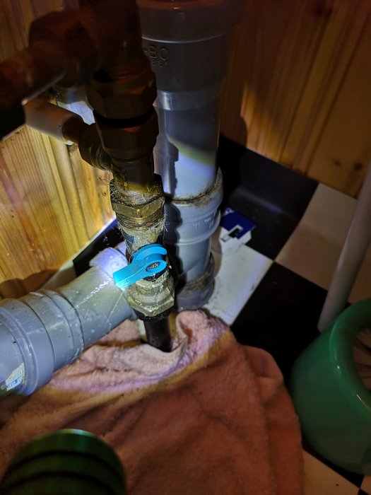 VVS-installation med synliga vattenrör och ventiler, några rör verkar läcka och är omslutna av handdukar.