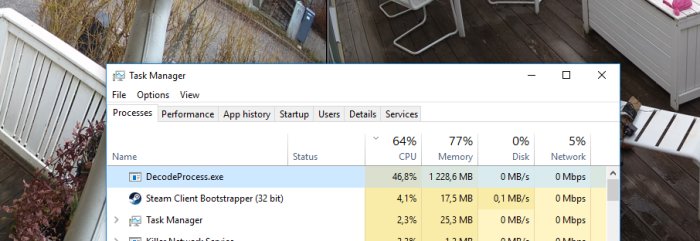 Datorskärm med Task Manager öppet visar hög CPU-användning bakom suddig bild av altan.