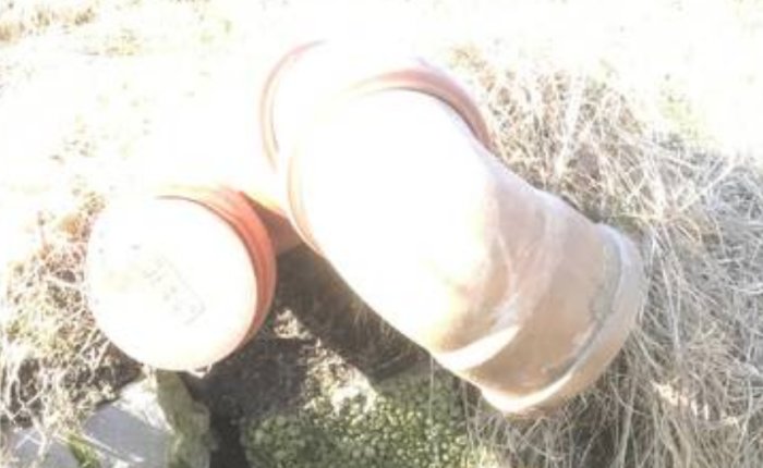 Ljusöverexponerad bild av Y-förgrening i avloppsrör med oklar funktion i gräs.