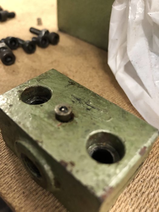 Närbild av en grön metalllagerenhet från en bänksvarv med synliga smörjningshål och gammalt smörjmedel.