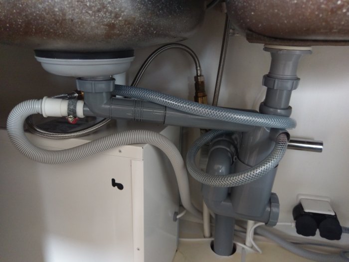 Rörinstallation under diskbänk med temporära lösningar för avlopp och anslutningen till en varmvattenberedare.