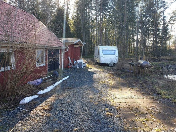 Grusad gårdsplan med lada och husvagn, väntar på idéer för hantering av varuleveranser.