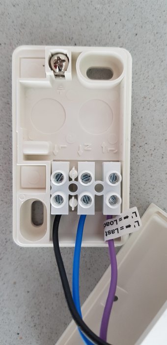 Elanslutningsenhet med öppet lock och synliga kablar och skruvanslutningar, föreslagen för installation av en rörelsesensor.
