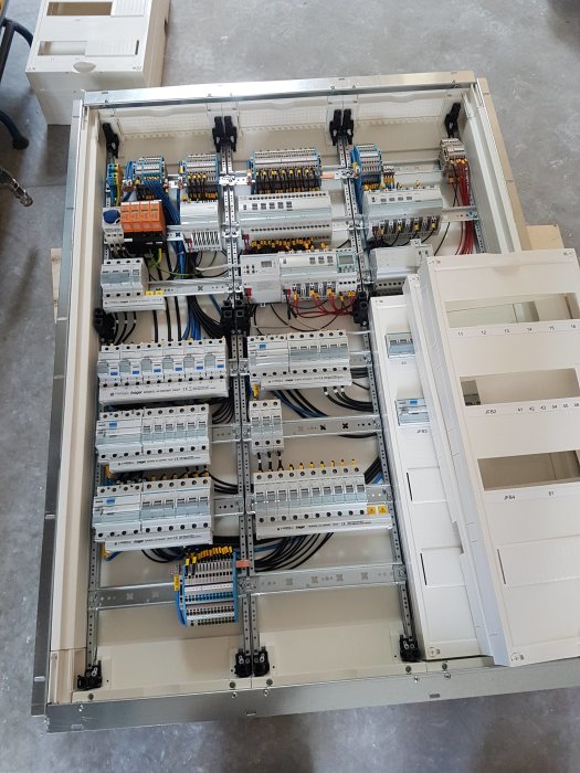 En öppen elcentral från Hager med en organiserad arrangemang av säkringar och ledningar, som visar KNX-​systemets detaljer.