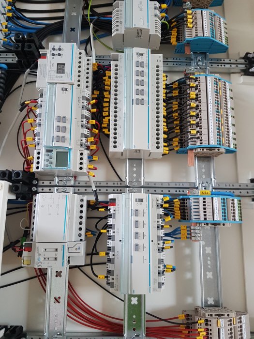 Elcentral med ett KNX-system med olika kopplingsutrustning och ledningar, installerat på vägg.