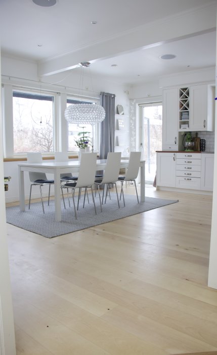 Ljust kök med vitmålade taklister och väggar, trägolv och modern inredning.