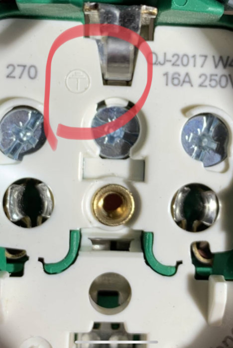 Närbild av en elektrisk komponent med markering runt ett tecken ingjutet i plasten.