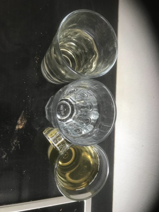 Tre glas står på en yta med vatten av varierande färg; klart, något grumligt och gult.