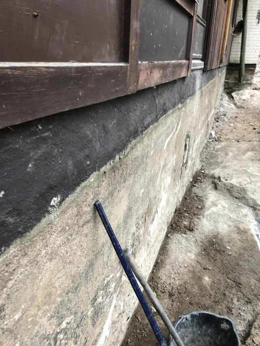 Grundmur av en byggnad med synlig fuktskada och avskalad färg, delvis upptäckt för renovering.