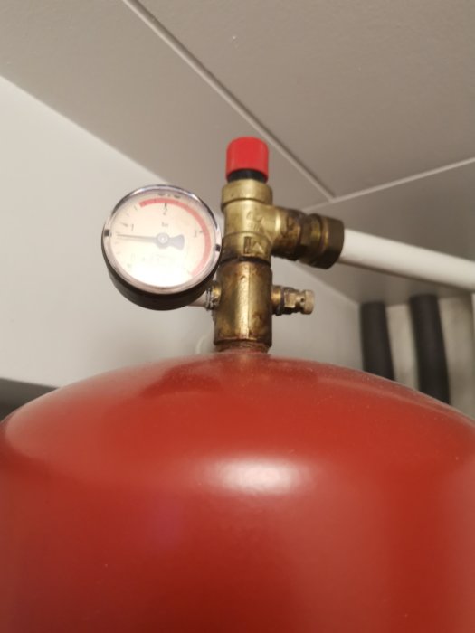 Manometer med lågt tryckvärde på en röd expansionskärl för värme- eller vattensystem.